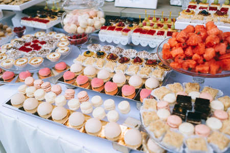 Wedding candy bar with different colored bright cupcakes, macaroons, cakes, jelly and fruits.の写真素材