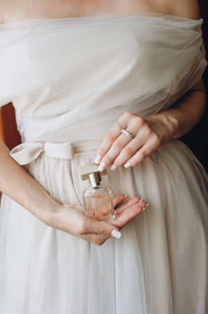 Close up of elegant perfume in a glass bottle in the hands of the bride in a wedding dress.の写真素材