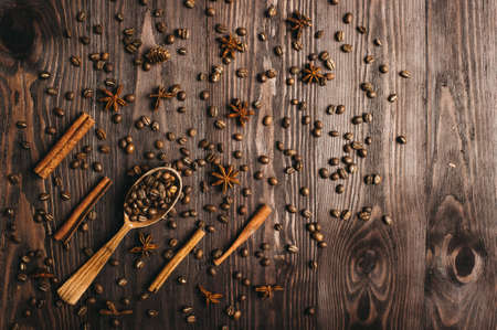Top view of wooden vintage spoon, coffee beans, cinnamon and star anise on wooden background.の写真素材