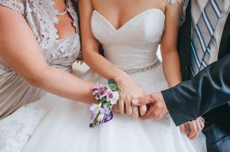 Mother and father holding hands of his daughter - young bride at her wedding day.の写真素材