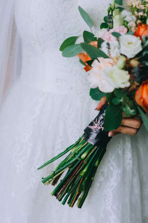 Beautiful wedding bouquet in the hands of the bride in a wedding dress. Floral arrangement.の写真素材