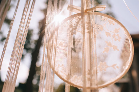 Close up element of wedding decor wooden circle with lace or tulle hanging outdoors.