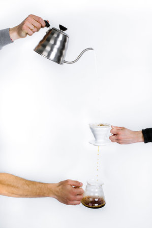 Human hands on a white background pour coffee through a special filter.の写真素材