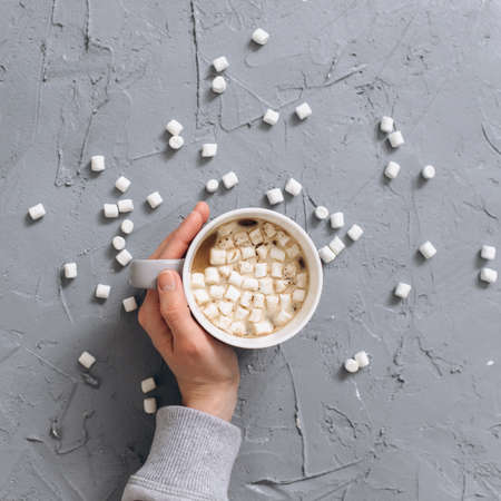 Woman holding cup of hot coffee on gray cemented back ground. Top view.の写真素材