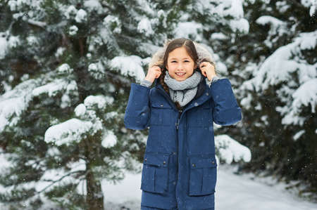portrait of a beautiful caucasian girl on a background of snow-covered Christmas trees.の写真素材