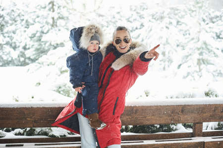 A Beautiful young mother with children in winter, near the house with a snow covered christmas treesの写真素材