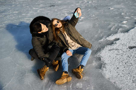 happy couple hugging and laughing outdoors in winterの写真素材
