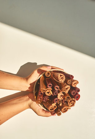 Hands holding a glass of pastilles on a white sunny background.