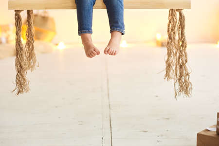 Little boy's legs while he is sitting on an indoor swingの写真素材