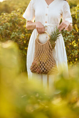Girl holding a wicker bag with fruits.の写真素材
