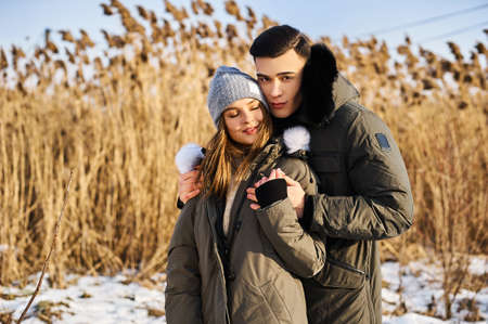 happy couple hugging and laughing outdoors in winter.の写真素材