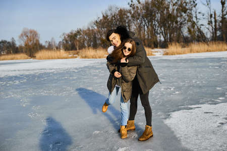 happy couple hugging and laughing outdoors in winterの写真素材