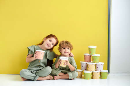 Two little boy and girl in with paper boxes. Design and advertising idea for packaging.の写真素材