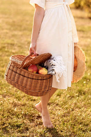 Girl stands in the middle of the field holding a basket in her hands.の写真素材