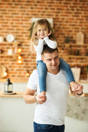 Little daughter with her father have a fun and playing in the kitchen on a brick background with a blurred lightsの写真素材