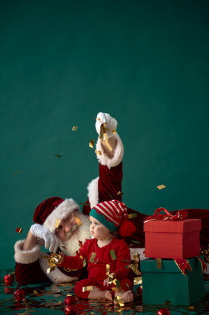 small child in Christmas pajamas with gifts and Santa Claus on a green backgroundの写真素材