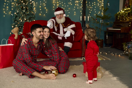 santa and young family at home playing with little baby childの写真素材