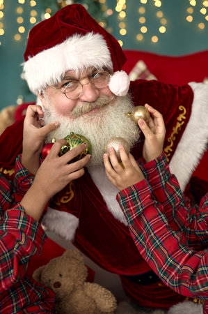 two african american sisters playing with santa claus beard at homeの写真素材