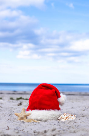Santa Claus hat and starfish on the sandy beachの写真素材