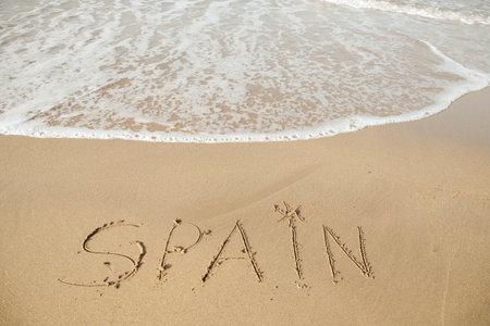 Spain lettering on the beach with wave and clear blue sea.の写真素材