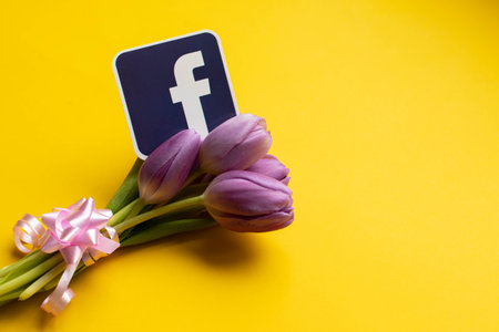RIGA,LATVIA-APRIL 25,2022.Facebook icon and spring fresh tulips on yellow background for mothers dayのeditorial素材