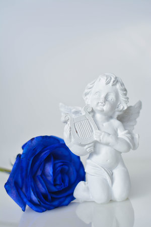 Cherub statue with blue rose on white background