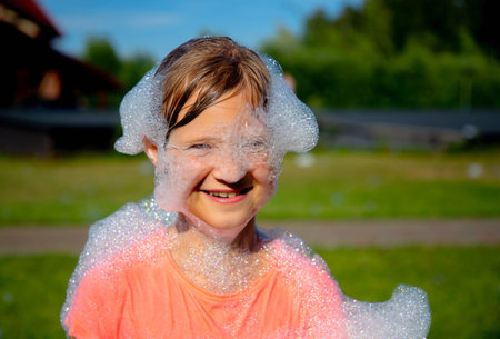 Cheerful kid girl playing with bubbles outdoorsの写真素材