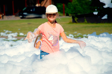 Child girl playing in outdoor foam partyの写真素材
