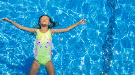 Child enjoys a sunny day floating in a bright blue swimming pool during summer