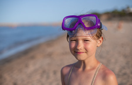 Young girl wearing snorkeling goggles at sunny beachの写真素材