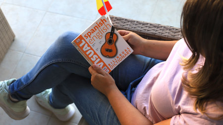 Woman reading Spanish-English dictionary featuring guitar illustration