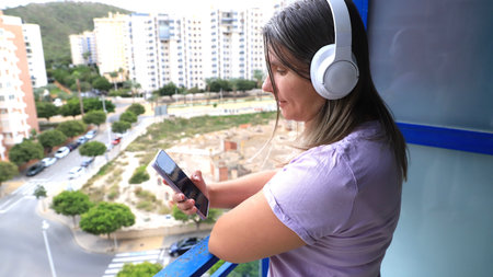 Woman with long hair wearing headphones listens to music on smartphone