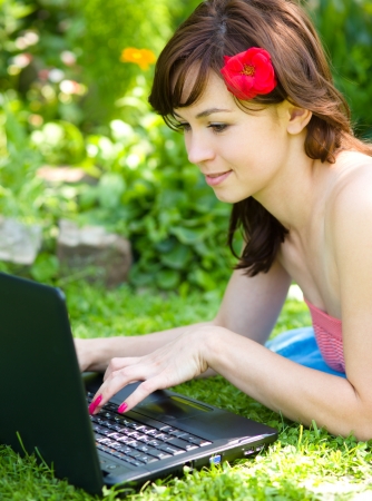 Young woman is playing on laptop, outdoor shootの写真素材
