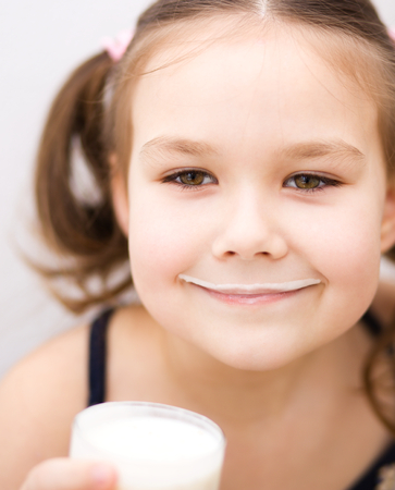 Cute little girl with a glass of milkの写真素材