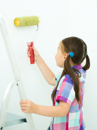 Happy cute girl as a construction worker with paint rollerの写真素材