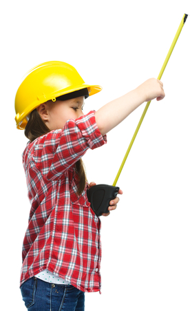 Happy cute girl as a construction worker with tape measure, isolated over whiteの写真素材