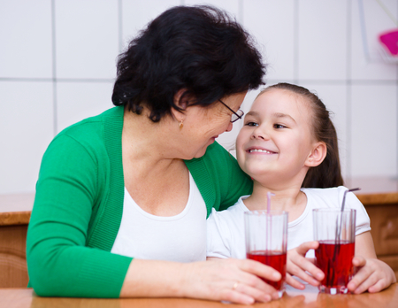 Grandmother with her grandchildren drink fruit juice, indoorsの写真素材
