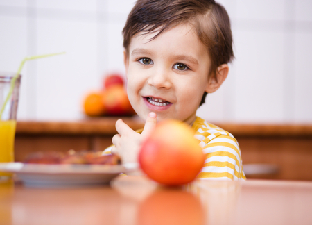 Little boy is drinking orange juice using strawの写真素材