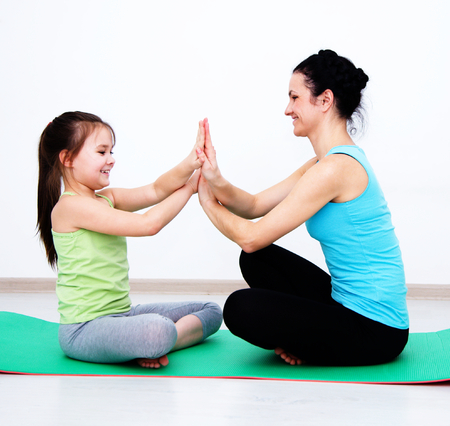 Cute mother and daughter doing exercise homeの写真素材