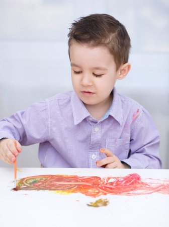 Portrait of a cute little boy playing with paintsの写真素材