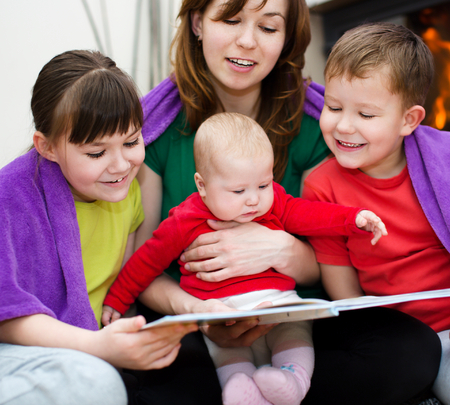 Happy mother is reading book with childrenの写真素材