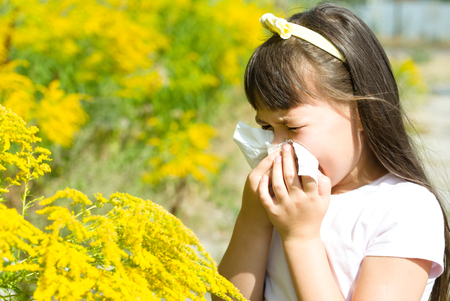 Girl is blowing her nose, allergic to bloom flowersの写真素材
