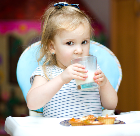 Cute cheerful little girl with a glass of milkの写真素材