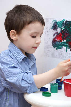 Portrait of a cute little boy playing with paintsの写真素材