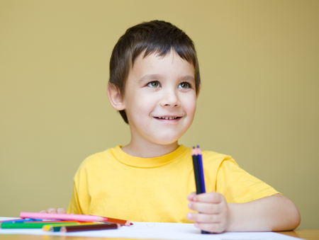 Little boy is holding bunch of color pencilsの写真素材