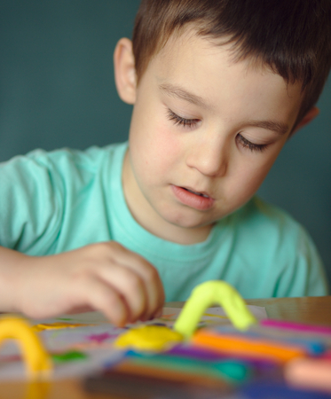 Happy boy playing with color play doughの写真素材