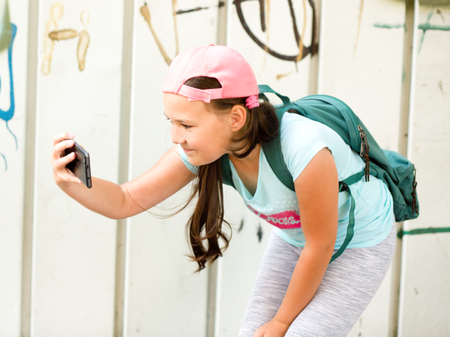 Happy cute girl having fun taking selfie outdoorsの写真素材