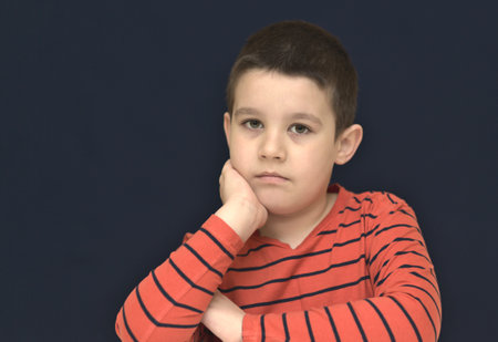 Portrait of a cute boy looking doubtful. Education concept. Dark background