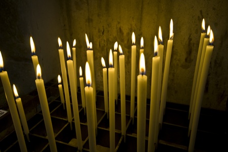 a bunch of long candles in an old dark church の写真素材