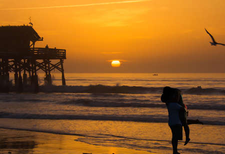 Silhouette of lovers kissing on the beach and sunrise.の素材